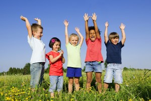 Multi-Ethnic group of children outdoors, arms raised